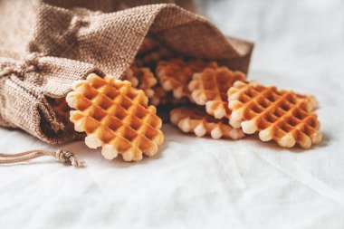 Beyaz bir tekstil arka planının üzerinde pamuk torbadaki küçük waffle 'lar.