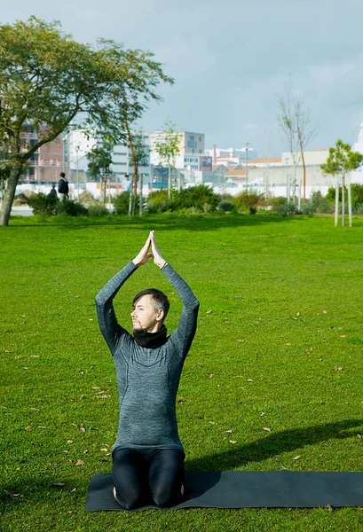Middle aged man doing breathing, relaxation, yoga, stretching, exersice, workout in the park using yoga mat. Natural beginner yoga posing. Healthcare concept.