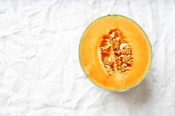 Organic Cantaloupe melon cut in half on the white linen cloth. Vegan snack concept. Top View. Flat Lay