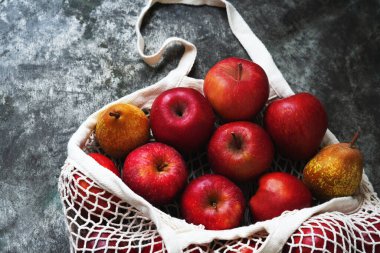 Elmalar metal bir arka planda ağ torbasında duruyor. Sürdürülebilirlik ve bilinçli tüketim kavramı. Üst Manzara. Düz Yat