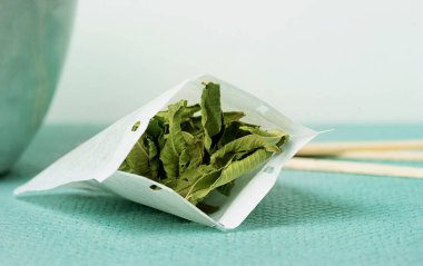 Lemon Verbena tea in a  hand made teabag over a tidewater green background. Selective Focus. Close Up clipart