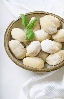 Geleneksel İtalyan patates gnocci (makarna) fesleğen yaprağı, yumurta ve unla süslenmiş. Pişmemiş makarna konsepti.