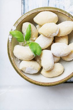 Geleneksel İtalyan patates gnocci (makarna) fesleğen yaprağı, yumurta ve unla süslenmiş. Pişmemiş makarna konsepti. Üst Manzara. Düz Yat