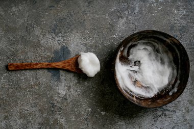 Hindistan cevizi kâsesinde Hindistan cevizi kaşığıyla sade arka planda duran organik hindistan cevizi yağı. Sürdürülebilirlik kavramı. Üst Manzara. Düz Yat.