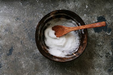 Hindistan cevizi kâsesinde Hindistan cevizi kaşığıyla sade arka planda duran organik hindistan cevizi yağı. Sürdürülebilirlik kavramı. Üst Manzara. Düz Yat.