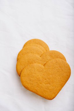 Kalp şeklinde zencefilli kurabiyeler beyaz tekstil arka planında. Düz Yat. Üst Görünüm