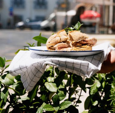 Geleneksel Portekizli sandviçi arka planda tutan adam. Sokak yemekleri konsepti