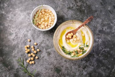 Ev yapımı humus kasesi, kaynamış nohut, otlar ve kırsal metal arka planda zeytin yağıyla süslenmiş. Üst Görünüm.