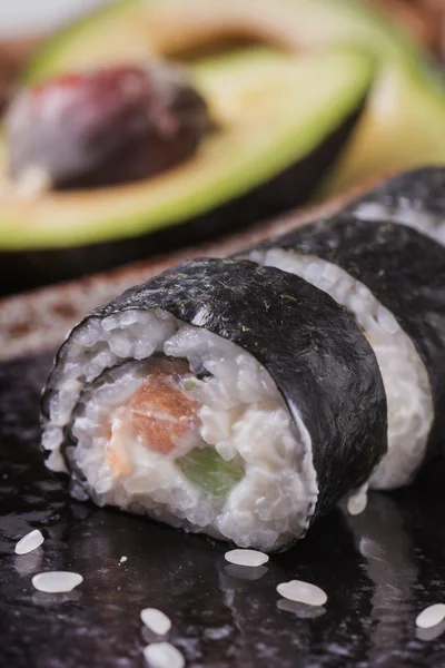 Maki-Sushi-Röllchen mit Lachs und Avocado auf dem alten Japaner — Stockfoto