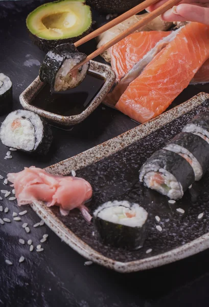 Maki rollos de sushi con salmón y aguacate en la vendimia japonesa —  Fotos de Stock