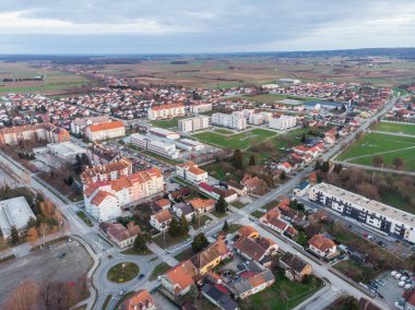 Koprivnica Şehri, Hırvatistan. Şehir merkezinin panoramik drone fotoğrafları kışın gün batımında çekildi. Şehir caddesi, park ve kilise manzarası.