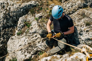 Kayalık bir uçurumdan iple inen genç bir adam sekiz figürlü ve karabinalı bir iple ipe bağlanmış. Dağlarda zorlu bir macera..