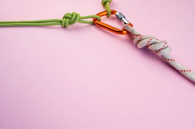 İple turuncu karabina. Tırmanma, dağcılık, dağcılık ve iple inme ekipmanları. Güvenlik halatı. Sekiz düğüm. Pembe arka planda izole edilmiş. En küçük kavram, kopyalama alanı.