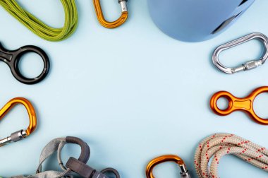 Tırmanan macera ekipmanları düz görünüm. Miğfer, karabina, ip, eldiven, radyo, koşum takımı, sekiz figür gibi ekstrem tırmanma araçlarının üst görüntüsü. Modaya uygun mavi arkaplan kavramı.