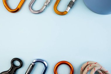 Tırmanan macera ekipmanları düz görünüm. Miğfer, karabina, ip, eldiven, radyo, koşum takımı, sekiz figür gibi ekstrem tırmanma araçlarının üst görüntüsü. Modaya uygun mavi arkaplan kavramı.