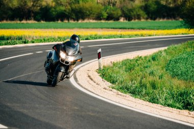 Motosiklet sürücüsü asfalt yolda tek başına gidiyor. Boş yoldaki hareketli motorcunun yaşam tarzı fotoğrafı