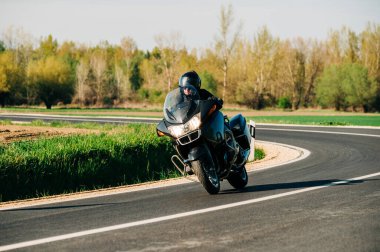 Motosiklet sürücüsü asfalt yolda tek başına gidiyor. Boş yoldaki hareketli motorcunun yaşam tarzı fotoğrafı