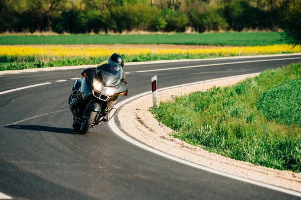 Motosiklet sürücüsü asfalt yolda tek başına gidiyor. Boş yoldaki hareketli motorcunun yaşam tarzı fotoğrafı