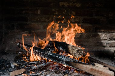Barbekü yapmak için alevler içinde yanıyor. Şöminede yanan odun tuğlalardan yapılmıştır..