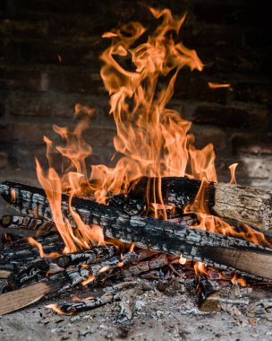 Barbekü yapmak için alevler içinde yanıyor. Şöminede yanan odun tuğlalardan yapılmıştır..