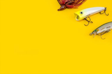 Sarı renkli arka planda levrek balıkçılığı kavramı. Düz yatış stili. Balık oltası, yumuşak silikon yemler, dönen yem ve yalpalayıcılar.. 