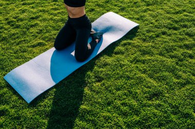 Güneşli bir günde çimlerin üzerinde yoga yapan güzel bir genç kız. Sağlıklı yaşam tarzı kavramı.