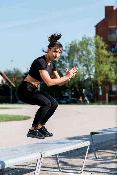 Jumping on the bench. Girl doing jump exercise outdoors. Fit woman healthy lifestyle concept.