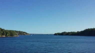 Kuzey Avrupa, İskandinavya, Archipelago 'da bir yaz günü. Suyun ve kayalık adaların üzerinde uçan hava aracı. Yelkenli tekneleri, evleri, villaları, iskelesi, rıhtımı ve mavi gökyüzü olan denizi olan..