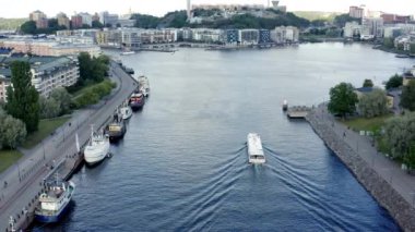 Stockholm, İsveç. Hava aracı, Hammarby Sjstad 'daki göl ve körfez manzaralı, modern mimarisi, gezici teknesi ve eski yüzen evleriyle hala havada asılı duruyor..