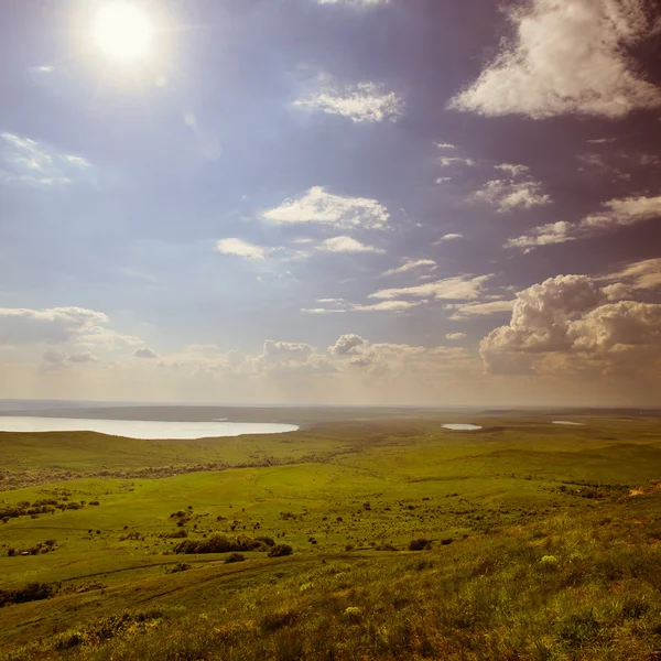 Foto de hermoso paisaje con tierra cubierta de hierba bajo cielos soleados en estilo vintage — Foto de Stock