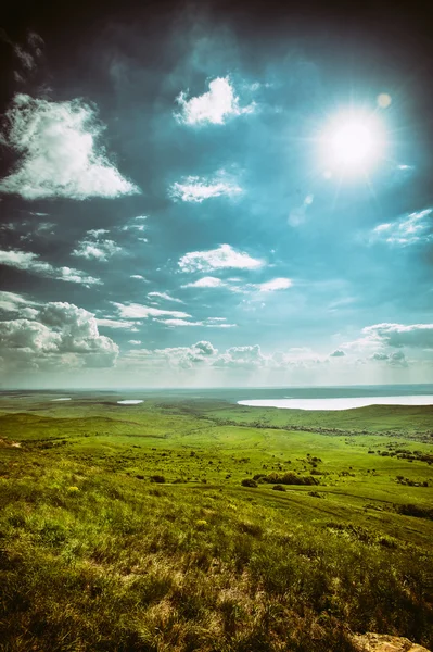 Foto de paisaje hermoso dramático con tierra herbosa bajo cielos soleados — Foto de Stock