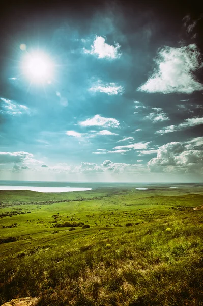 Foto van dramatische prachtige landschap met gras begroeide land onder zonnige hemel — Stockfoto