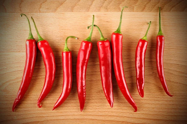 Red hot peppers on wood board — Stock Photo, Image