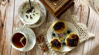 Küçük peynirli kekler, böğürtlenler, çikolata ve klasik İngiliz porselenleriyle şenlikli çay partisi.