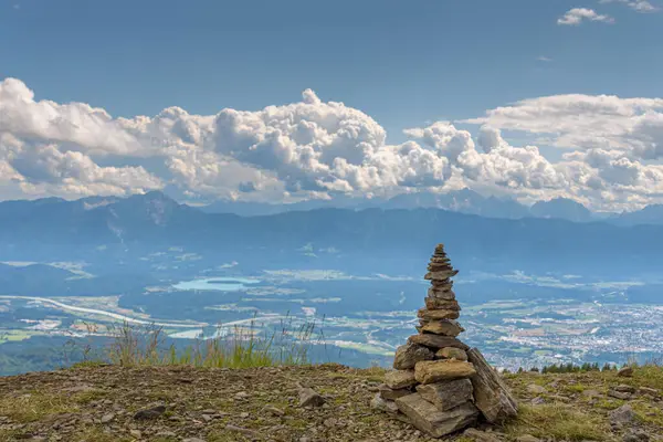 Dağın tepesinde, arka planda köy ve bulutlu mavi gökyüzü olan taşlar yığını. Denge ve uyum kavramı