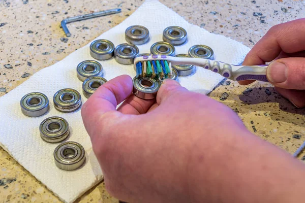 Adam diş fırçasıyla bilye temizliyor.