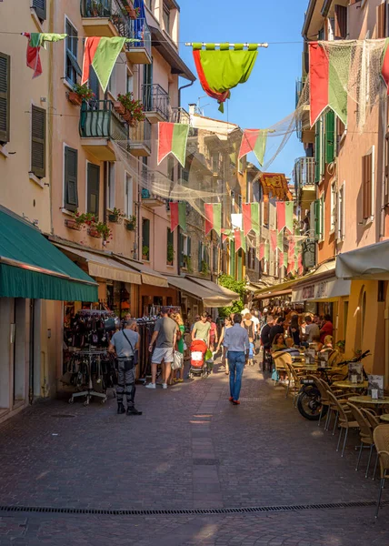 İnsanlar Garda Gölü kıyısındaki Lazise kasabasında alışveriş caddesinde yürüyorlar.