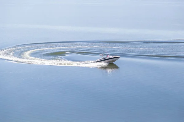 Güneşli bir günde cam bir gölde sürat teknesi U dönüşü