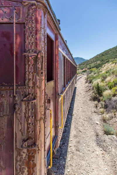 Raylarda giden yıpranmış kırmızı tren vagonu.
