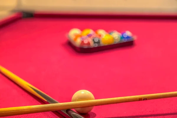 Paus e bolas de bilhar em uma mesa de bilhar vermelha — Fotografia de Stock