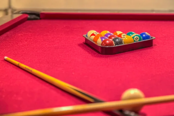 Kırmızı bilardo masasında bilardo topları var.