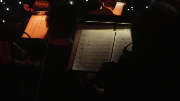 Sekcji String Orchestra jest siedzi podczas przerwy przed wykonywania największych przebojów przez Rock Symphony koncert dyrygent Nikolai Lysenko — Wideo stockowe