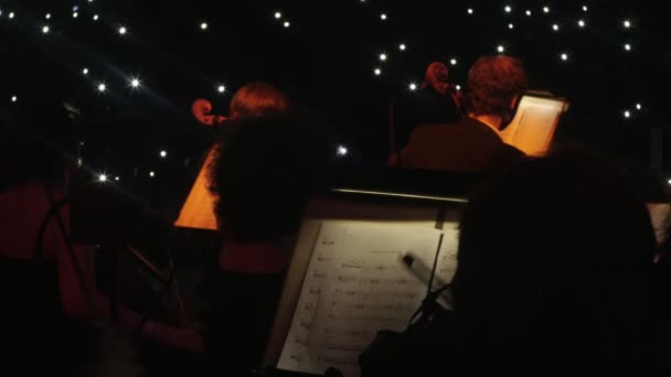String Family of an Orchestra is Performing Music Lights Desligado Livros de Música Iluminados por Lanternas Rock Symphony Concert Conductor Nikolai Lysenko — Vídeo de Stock