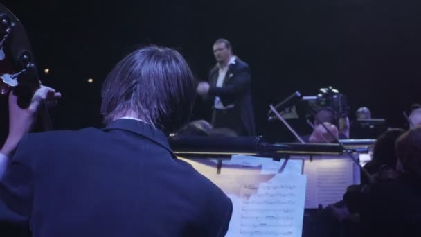 Rock Symphony Los grandes éxitos La dirección de orquesta Los músicos están tocando violín y contrabajo Libros de música en el escritorio El director Nikolai Lysenko — Vídeos de Stock