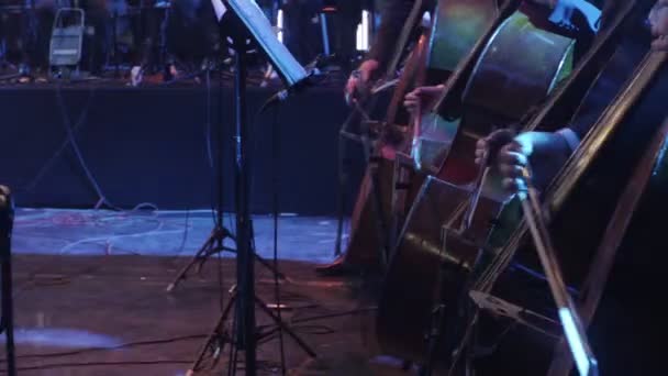 Musiciantes estão tocando baixos duplos com pessoas de arco na orquestra está tocando sincronicamente em instrumentos de cordas os maiores acertos por sinfonia rock — Vídeo de Stock