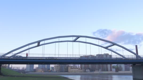 Personnes Les silhouettes marchent à l'arc Voitures de pont Les minibus sont conduits par un pont sur une rivière Les gens sur un pont Maisons à plusieurs étages Paysage urbain — Video