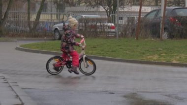 Çocuk Bisikletüzerinde Oturuyor Tekerlekli Bisiklet Eforlar Zor Little Girl Bir City Street Park Arabaları tarafından Bisiklet İki Tekerlekli Bisiklet Sürme yapıyor yapmaya başlar