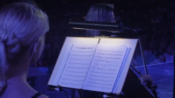 Kvinnor spelar cello med en båge musikböcker på Stand the Greatest Hits av Rock Symphony ukrainska Tour konsert i Kiev dirigent Nikolai Lysenko — Stockvideo