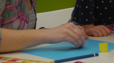 Eller bir eğri ile iki kız çocuk bir eğri ve eğitimci kardeş insanlar el yapımı hediyeler yapmak Are şarap bir iş parçacığı yapıştırmak bir mavi kağıt tutkal boya vardır