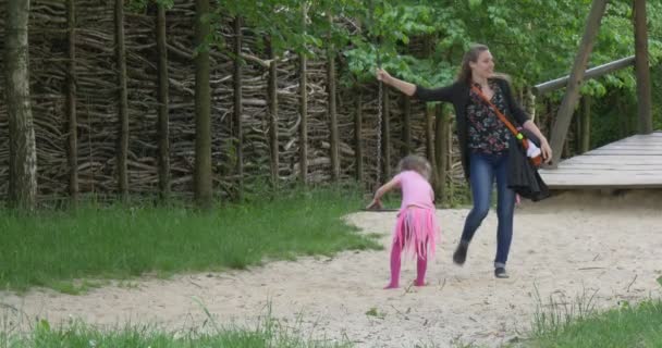 Счастливые мать и дочь на качелях детской игры на улице — стоковое видео